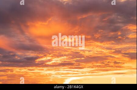 Bright orange sky during a sunset with dark clouds Stock Photo