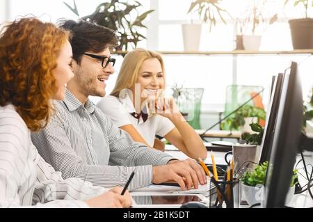 Positive millennial creative team discussing work issues Stock Photo