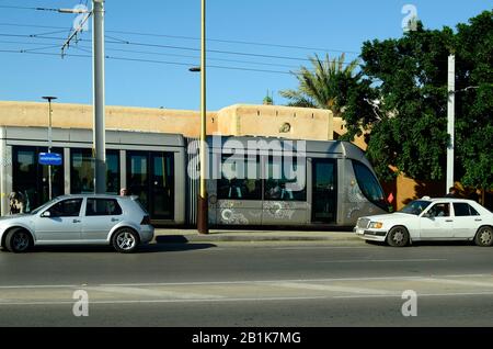 Meknes, Morocco - November 18th 2014: Unidentified people and modern tram, a public mode of transport, medieval city wall behind Stock Photo