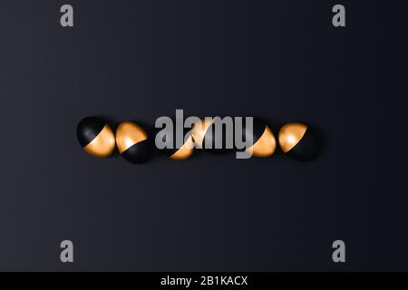 Six black and golden Easter eggs on a dark grey background. Flat lay, top view, copy space. Stock Photo