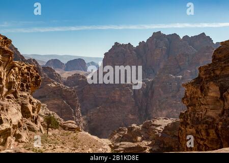 Desert view with cliff formations. Amazing scenes at Monastery Route, beautiful sunny hazy and dreamy day at Petra complex and tourist attraction, Hashemite Kingdom of Jordan Stock Photo