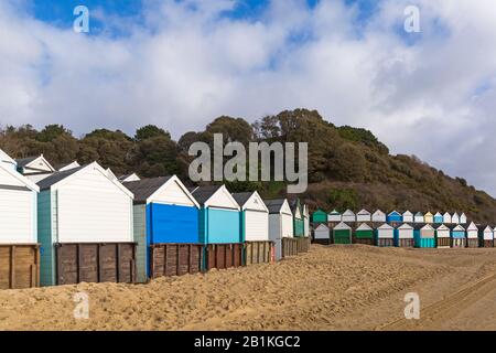 Beach huts at Middle Chine with promenade covered in sand from recent bad weather at Bournemouth, Dorset UK on a sunny cold day  in February Stock Photo