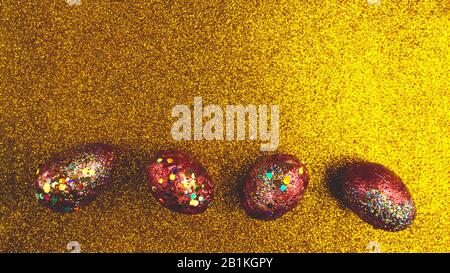 Red golden eggs. A symbol of making money and successful investment on festive gold background, copy space, selective focus Stock Photo