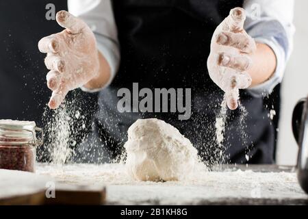 Cook kneads dough with flour on kitchen table stop motion Stock Photo