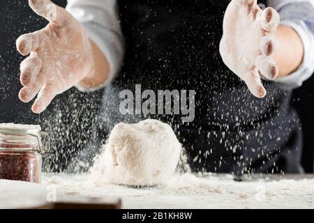 Cook kneads dough with flour on kitchen table stop motion Stock Photo
