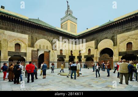 Fez, Morocco - November 20th 2014: Unidentified tourists in the inner courtyard of Medersa Bou Inania with artful ornaments  - a islamic school - madr Stock Photo