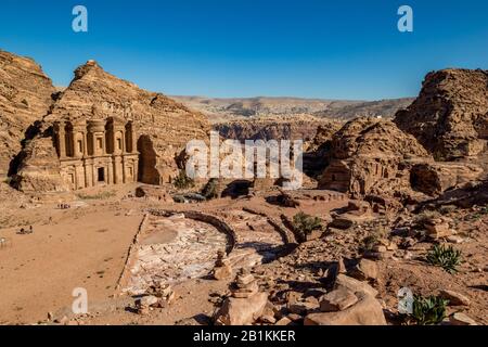 Ancient amphitheater and defocused sun-lit view of stunning Ad-Deir in ancient city of Petra, Jordan. Ad-Deir or The Monastery. Petra complex and tourist attraction, Hashemite Kingdom of Jordan Stock Photo
