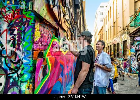 Two men, graffiti artists spray painting down graffiti filled alleyway, Hosier Street, Melbourne Lanes, Melbourne, Victoria, Australia Stock Photo