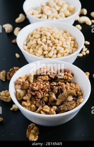 superfood concept, cedar, walnuts, cashew nuts in a plate on a black background Stock Photo