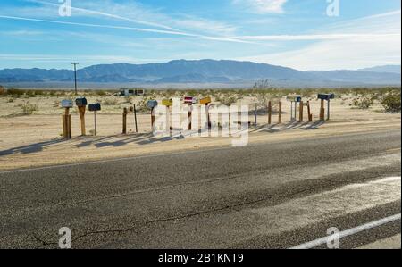 Mailboxes on the board of damaged road through Nevada desert. Stock Photo