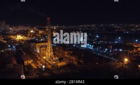 Aerial view of oil factory with gas tank , night city on background. Stock Photo