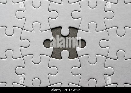 Blank, white jigsaw puzzle close up. One piece is missing Stock Photo