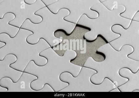 Blank, white jigsaw puzzle close up. One piece is missing Stock Photo