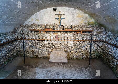 Hallstatt, Austria – July 9, 2016. Interior view of Beinhaus charnel house in St Michael chapel of Hallstatt, with rows of stacked skulls. A small cha Stock Photo