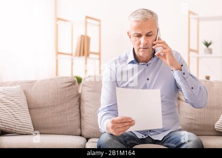 Senior man talking on mobile phone holding document Stock Photo