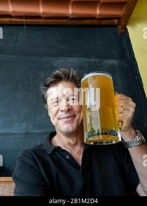 Handsome man with craft beer in the mug. German traditions. Elegant man drinking beer from a glass. Stock Photo