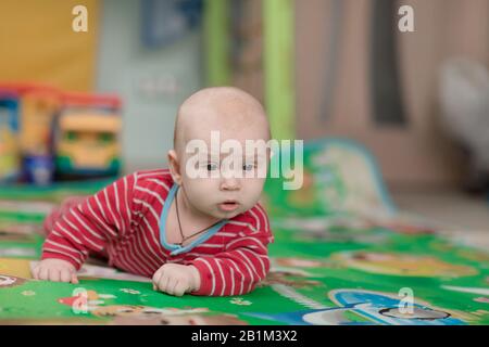 Cute little baby boy trying to lie on belly and crawling Stock Photo