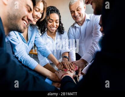 Coworkers Holding Hands During Teambuilding Meeting In Modern Office Stock Photo