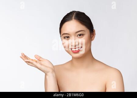 Young attractive asian woman who takes a capsule or pill. Isolated over white background. Stock Photo