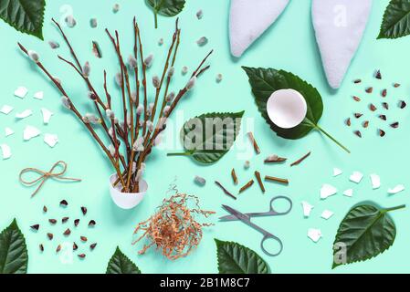 Ears of a hare, branches with kidneys, eggshells, green leaves, scissors on a light background. Easter spring flat-lay concept. Stock Photo