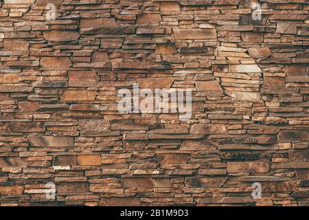 Abstract pattern of brown stone texture. Brick wall background. Rough granite surface. Cracked rock. Decorative tile on facade of building Stock Photo