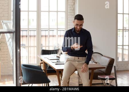 Middle eastern ethnicity businessman with smartphone in modern office room Stock Photo