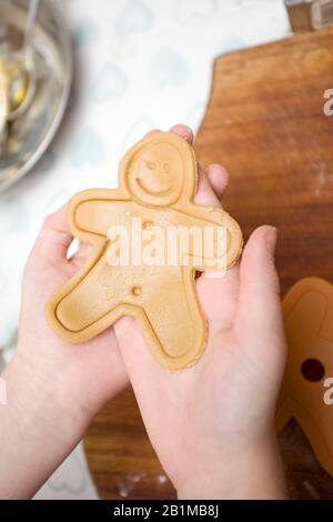 Child holding uncooked smiling gingerbread man Stock Photo