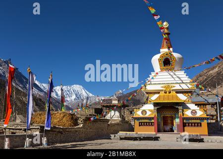 Massive Giant Stupa Buddhist Monument and Distant Snowy Himalaya Mountain Peaks in Manang Nepal Village on Annapurna Circuit Hiking Trek Stock Photo