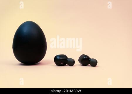 Black egg and black earphones on peach background.  Stock Photo