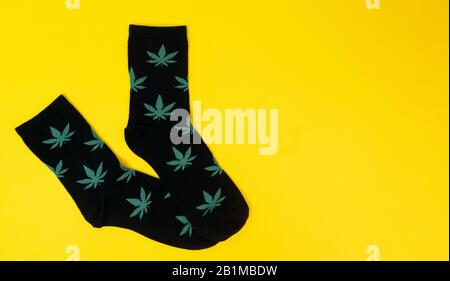 socks with cannabis leaves on yellow background Stock Photo