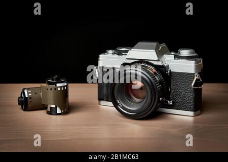 Classic analog 35 mm camera and film rolls vintage on wooden table Stock Photo