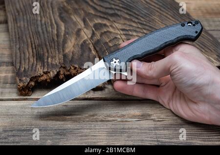 Folding knife in a hand. A man holds and shows a knife. Knife advertisement. Stock Photo