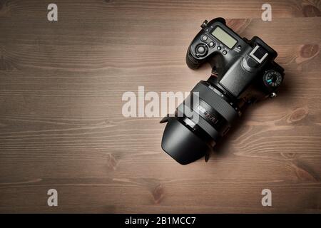 top view of a modern digital SLR with attached zoom lens and hood on wooden table Stock Photo