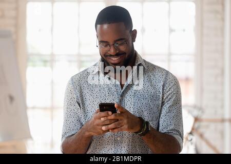 African guy holds phone using apps take break during workday Stock Photo