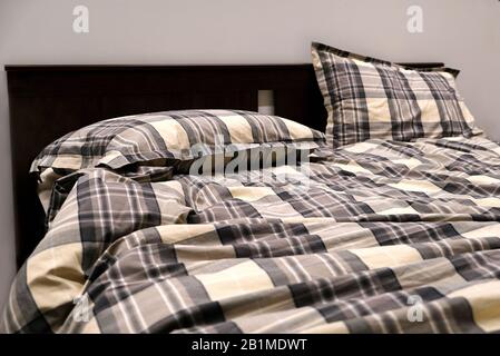 The sun shines through the bedroom window. Unmade bed blankets and pillows are not tucked in Stock Photo