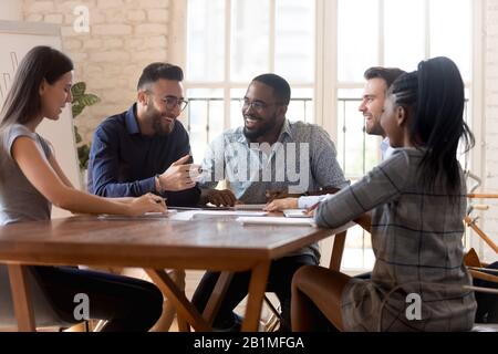 Diverse employees sitting at table having pleasant positive conversation Stock Photo
