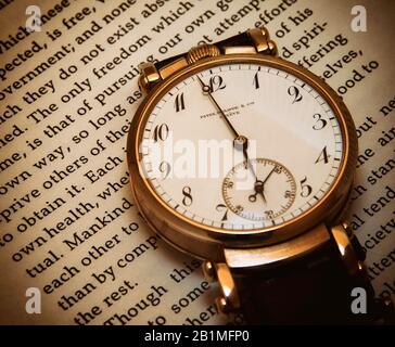 Free time - antique luxury wristwatch lying on text of a passage from philosopher John Stuart Mill, On Liberty.  Concept: liberty, adaptation. Stock Photo