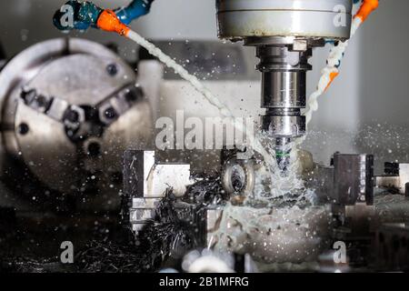 A process of vertical cnc steel milling with external water coolant streams, splashes and a lot of metal chips. Fast shutter speed for motion freezing Stock Photo