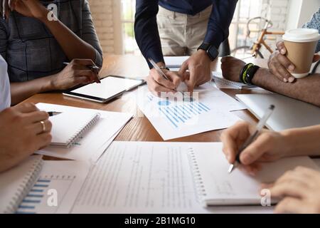 Closeup desk full with papers documents and diverse businesspeople hands Stock Photo