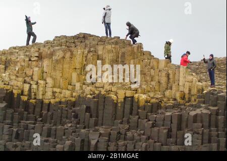 People atop basalt stone columns at Giant's Causeway Stock Photo