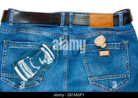 On the jeans is an empty glass bottle with a cork. Stock Photo