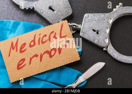 Handcuffs, a scalpel and medical gloves on the table. view from above. Medical error concept Stock Photo