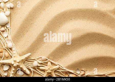 Seashells, starfishes and fishing net on sand background. Top view. Flat lay Stock Photo