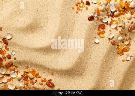 Ambers and seashells on sand background. Flat lay. Top view Stock Photo
