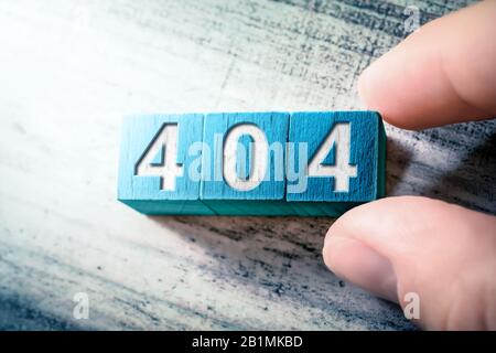 Error Code 404 On Blue Wooden Blocks On A Table, Arranged By A Hand Stock Photo