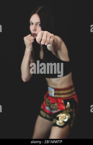 Tall girl throwing a punch in boxing pose, wearing muay thai boxing pants and black top. Royalty free stock photo. Stock Photo