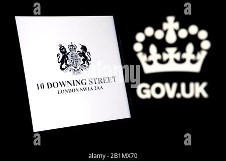 UK Prime Minister's Office logo glowing on the smartphone screen and gov.uk logo on the blurred dark background. Concept. Stock Photo
