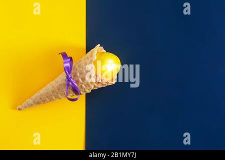 An icecream cone with an Easter egg in it on the bright colorful background. Happy Easter concept. Easter festive background. Top view Stock Photo
