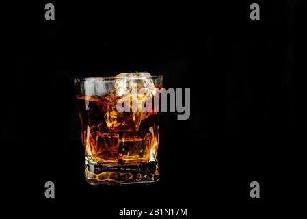 splash alcohol drink whiskey with ice  in a glass on a black background Stock Photo