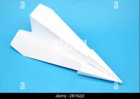White paper plane on blue background . Stock Photo